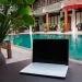 Digital nomad working besides pool - a laptop computer sitting on top of a table next to a pool.
