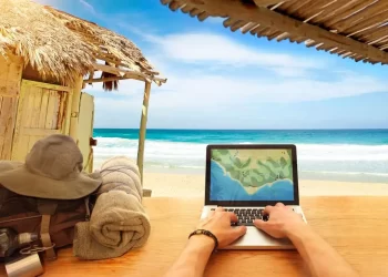 A digital nomad working on a laptop on a serene beach
