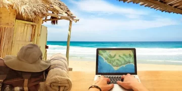 A digital nomad working on a laptop on a serene beach