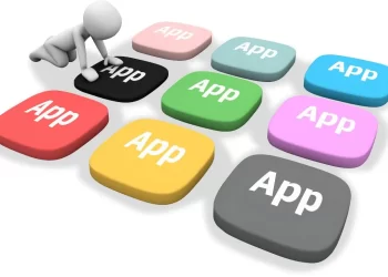 A person sitting on top of a keyboard with the words app on it - essential apps for digital nomads