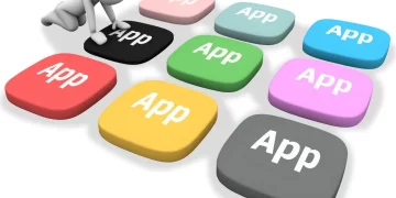 A person sitting on top of a keyboard with the words app on it - essential apps for digital nomads