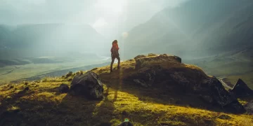 Digital nomad standing on a mountain with a backpack, embodying the spirit of adventure and remote work.